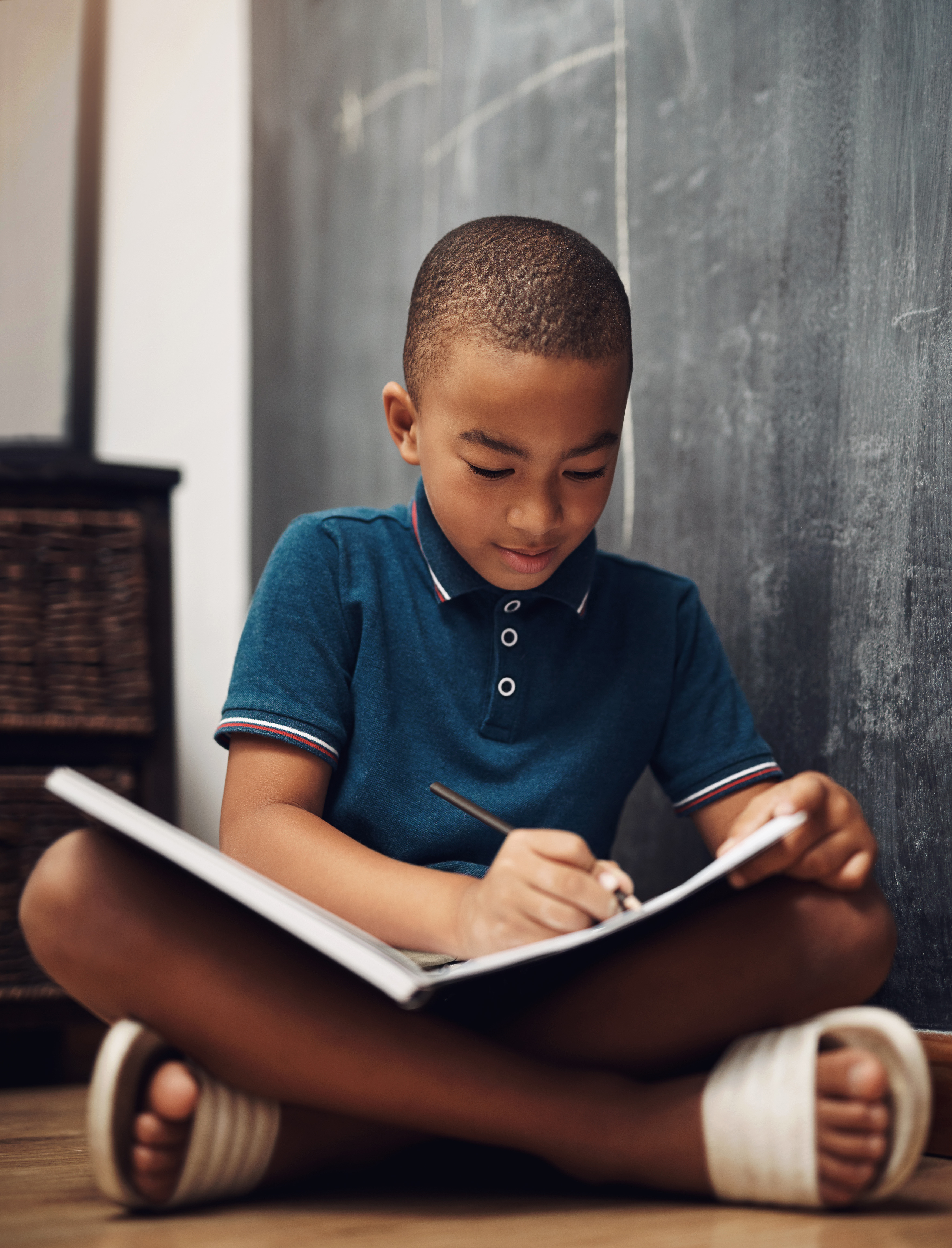 Student focused on schoolwork at a desk in front of a chalkboard